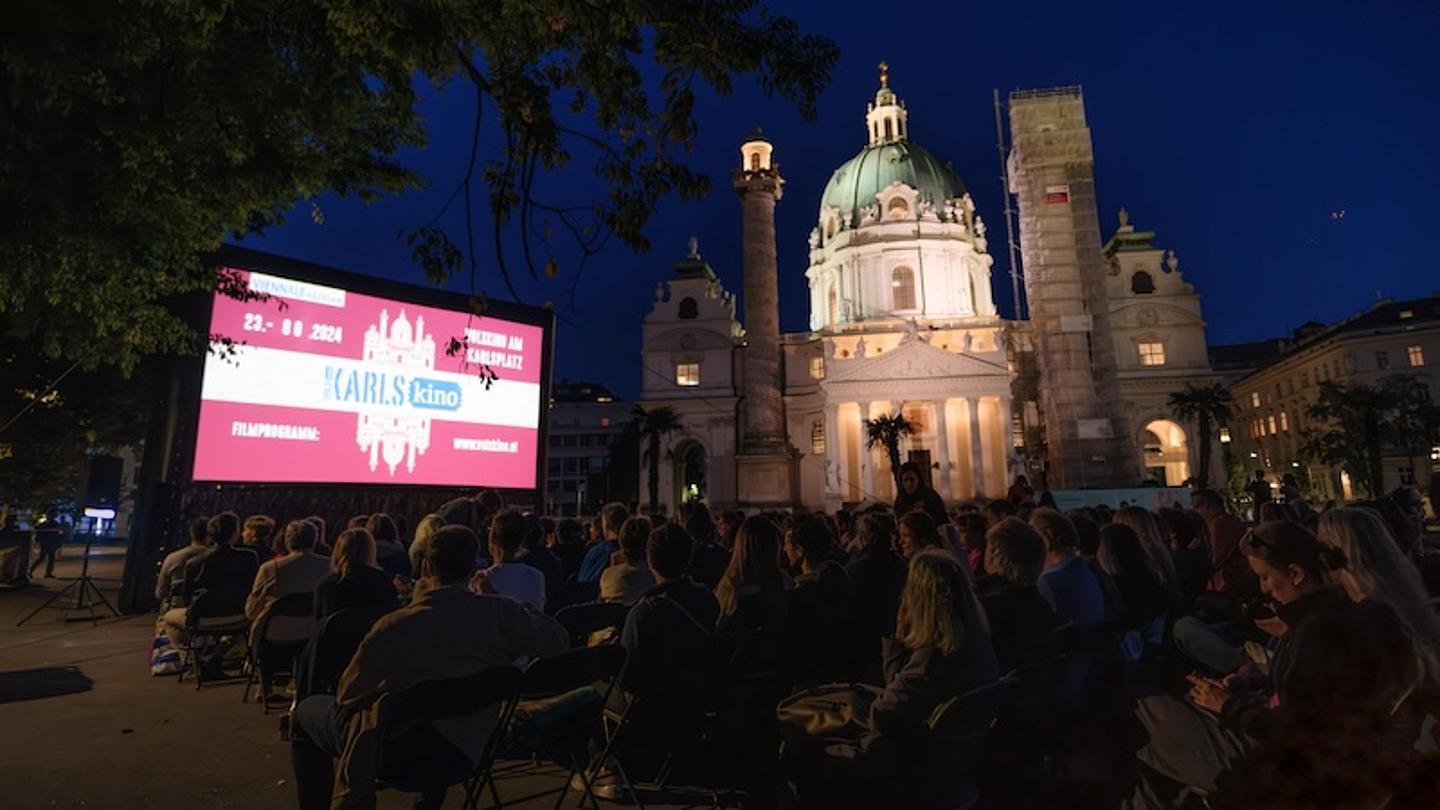 Karlskino bei Nacht vor beleuchteter Karlskirche