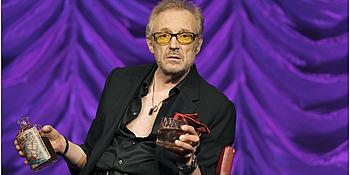 Hader auf der Bühne - gestikulierend und mit alkoholischem Getränk in der Hand