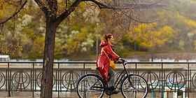  Frau mit rotem Regenmantel am Rad im Herbst