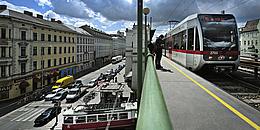 Bild von U-Bahn-Linie U6, die über die Brücke bei der Station Alser Straße fährt, während unter der Brücke eine Straßenbahn gerade ihre Station verlässt.