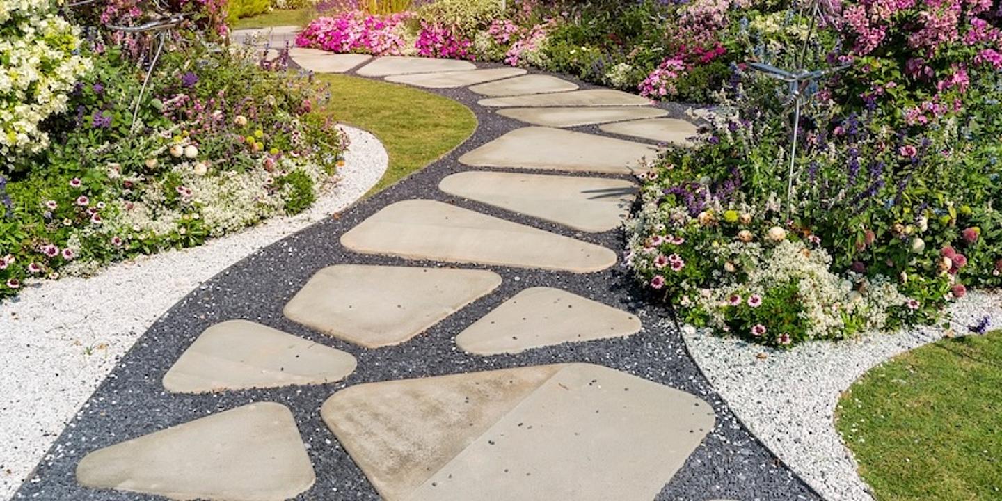 gartenweg mit steinplatten und schwarzem Kies dazwischen