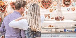 Zwei in Tracht gekleidete Personen stehen auf der Brunner Wiesn