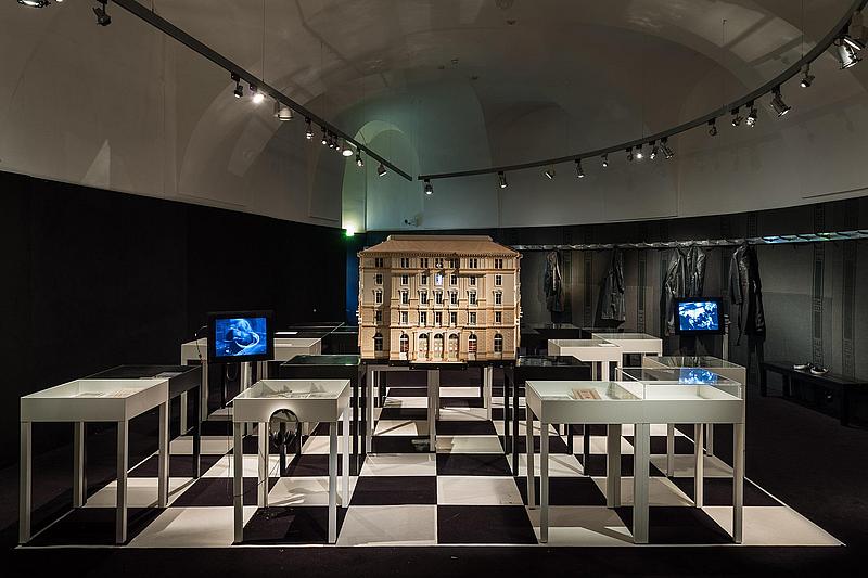 Ausstellungsraum des Theatermuseum mit schwarz weißen Flißen, diversen Ausstellungsvitrinen und dem Modell eines Hotels im Zentrum.