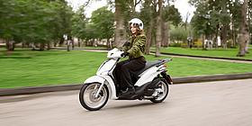 Frau fährt Piaggio Liberty 125 weiß auf der Straße