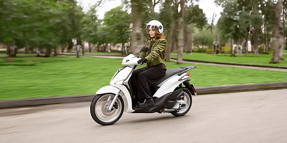 Frau fährt Piaggio Liberty 125 weiß auf der Straße
