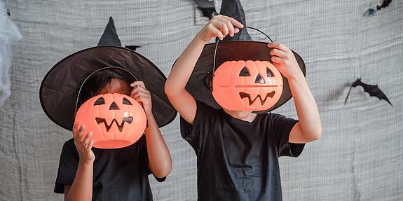 Halloween Kinder Zwei Kinder in Hexenkostümen mit Kürbislampen.