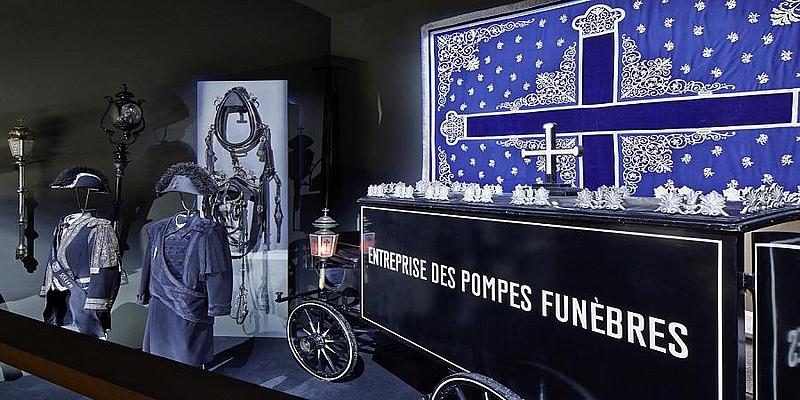 Ein alter Leichenwagen, zwei blaue Uniformen, ein Kreuz