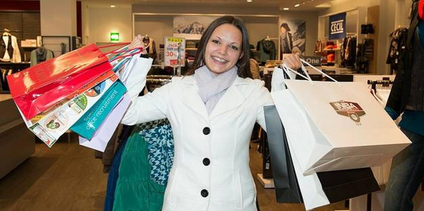 Mädchen hält glücklich mehrere Einkaufstaschen hoch