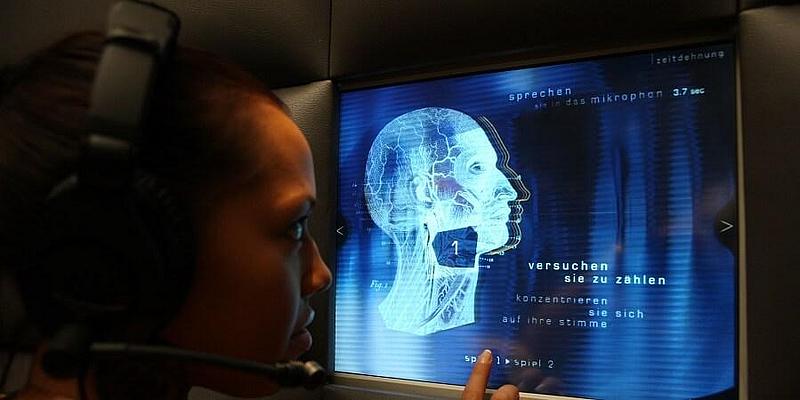 Mann der vor einem interaktiven Terminal steht und Kopfhörer aufhat