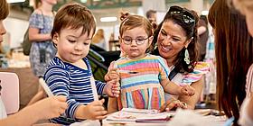 Mütter mit Kindern beim Basteln. 