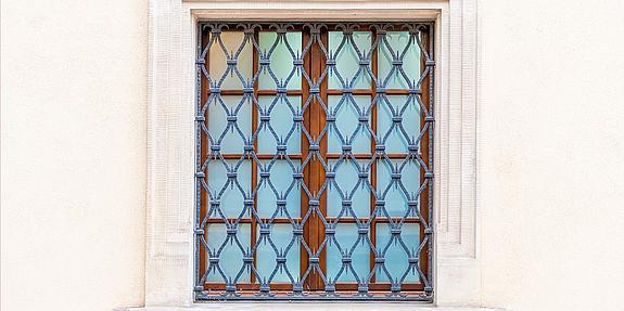 Fenstergitter vor Fenster an gelber Wand