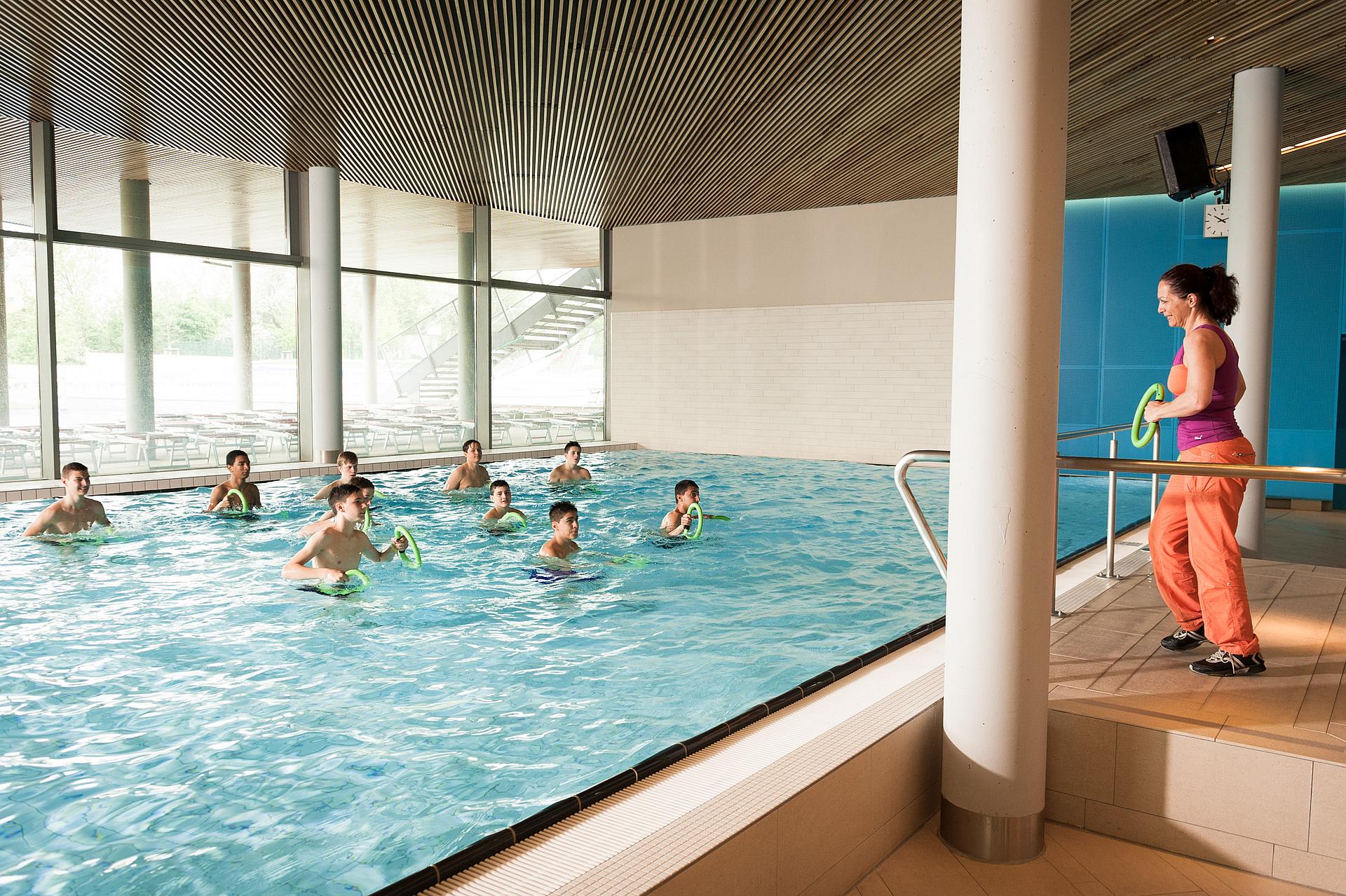 Frau gibt Übungen für Kinder im Schwimmbecken vor