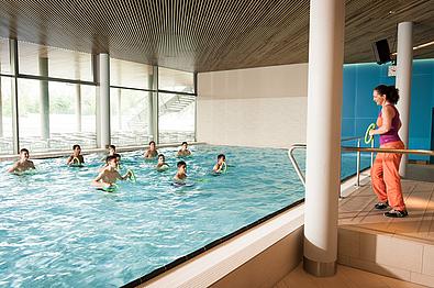 Frau gibt Übungen für Kinder im Schwimmbecken vor