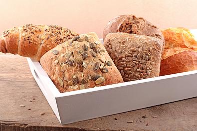 Brot und Gebäck in einer weißen Schüssel auf Holz