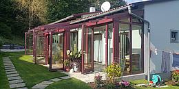 Wintergarten aus Glas von innen fotografiert mit weißen Rettansesseln