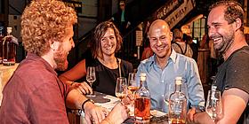 Vier Leute stehen bei einem Tisch und verkosten Rum