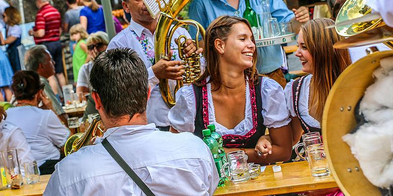 Zwei junge Frauen im Dirndl, Publikum am Neustifter Kirtag, im Hintergrund Blasmusik
