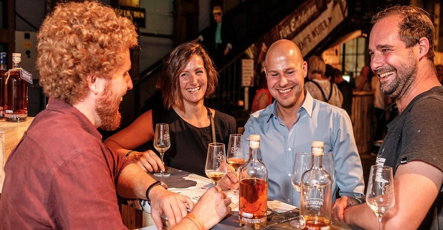 Vier Leute stehen bei einem Tisch und verkosten Rum