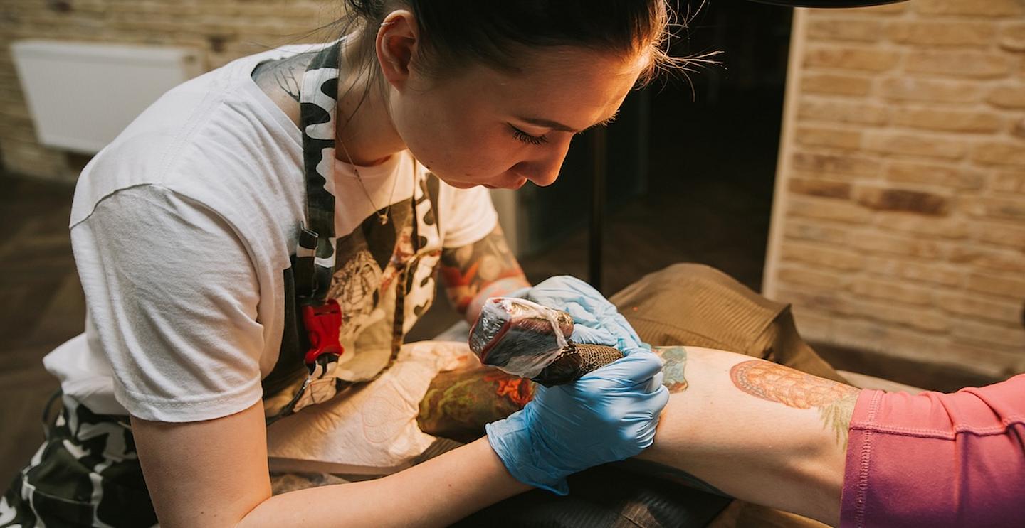 Junge Frau beim Tätowieren eines Unterarms