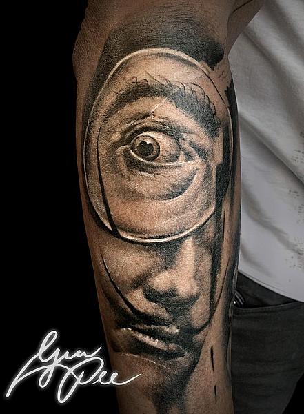 Tattoo Motiv des Künstlers Dalí mit Lupe am Unterarm