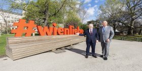 wienliebe Michael Ludwig und Walter Ruck vor einem Schild mit dem Schriftzug "#wienliebe" im Wiener Rathauspark.