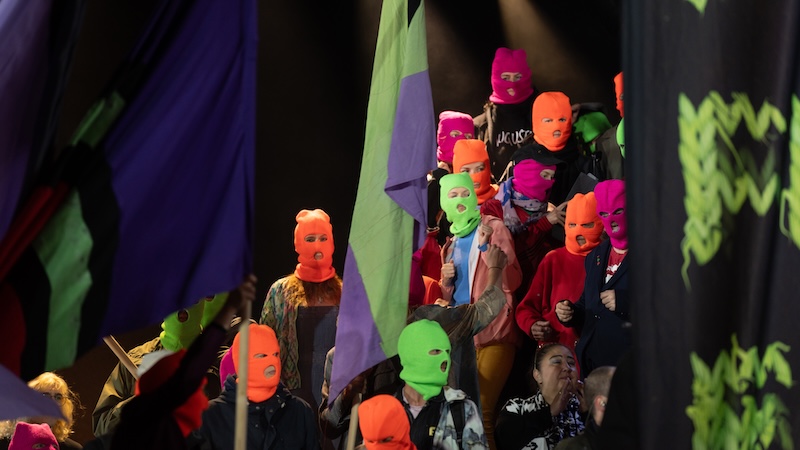 Personen mit neonfarbenen Sturmhauben bei der Eröffnung der Wiener Festwochen 2024.