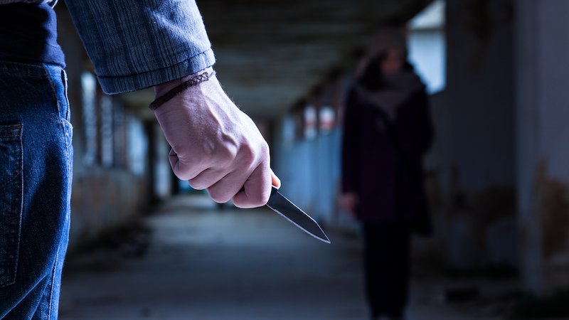 Person mit Springmesser lauert einer Frau auf.