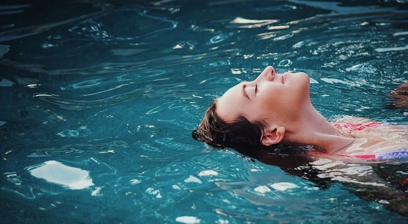 Frau liegt im Wasser und genießt es